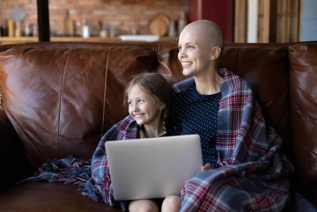Woman and daughter use laptop to contact Kim's hope and access glioblastoma financial aid funds on Kim's Hope.